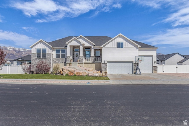 craftsman-style home featuring fence, stone siding, and board and batten siding