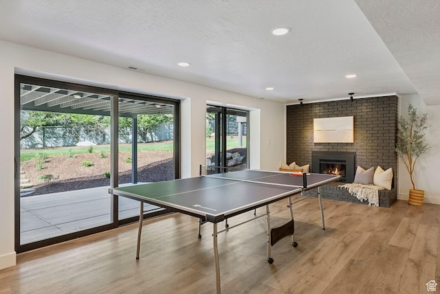 game room with recessed lighting, visible vents, light wood-style floors, baseboards, and a brick fireplace