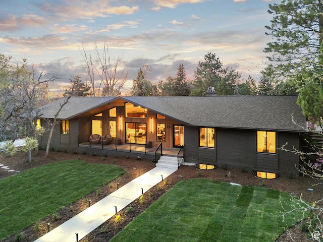view of front of house featuring a chimney, a yard, and a shingled roof
