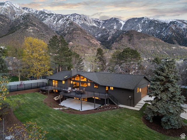 rear view of house featuring a yard, a deck with mountain view, and fence