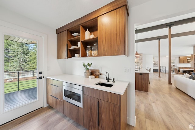 interior space featuring brown cabinetry, light wood-style flooring, light countertops, and a sink
