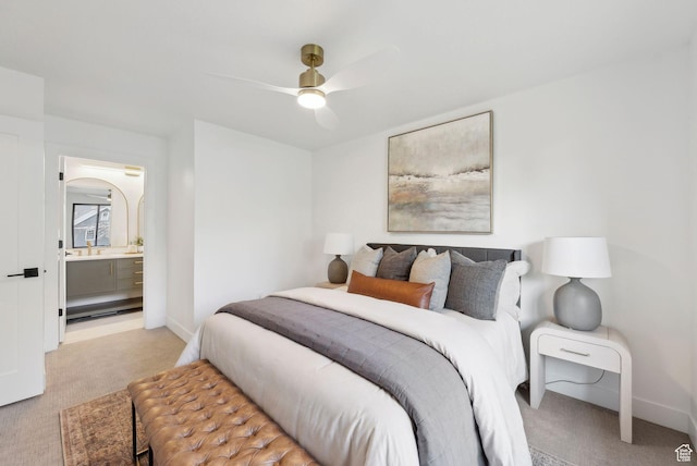 bedroom with ensuite bath, a ceiling fan, baseboards, and light carpet
