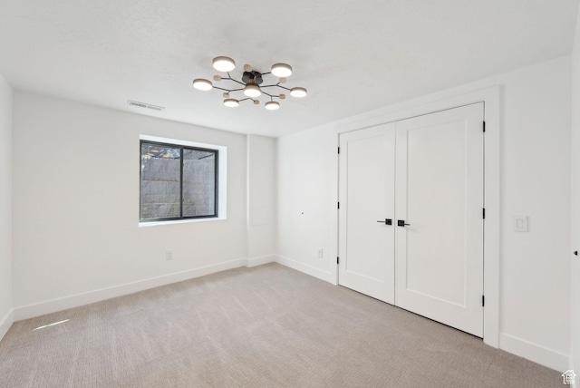 unfurnished bedroom featuring light carpet, baseboards, visible vents, an inviting chandelier, and a closet