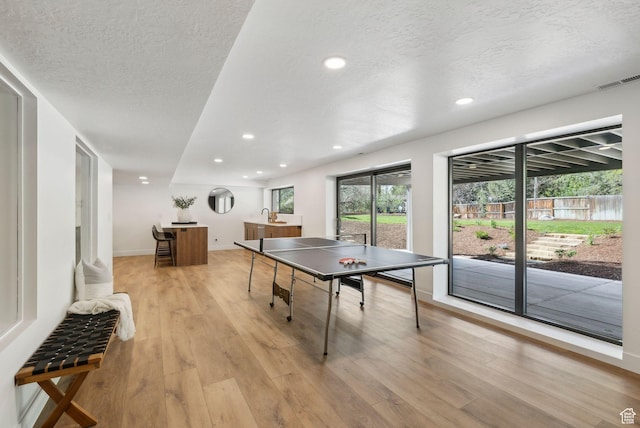 game room with recessed lighting, visible vents, a textured ceiling, and light wood-style floors