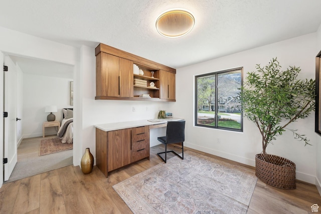 office featuring built in study area, baseboards, and light wood-type flooring