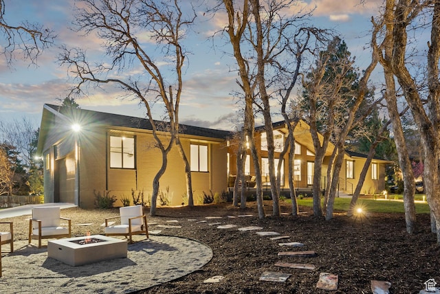 back of house at dusk featuring a fire pit
