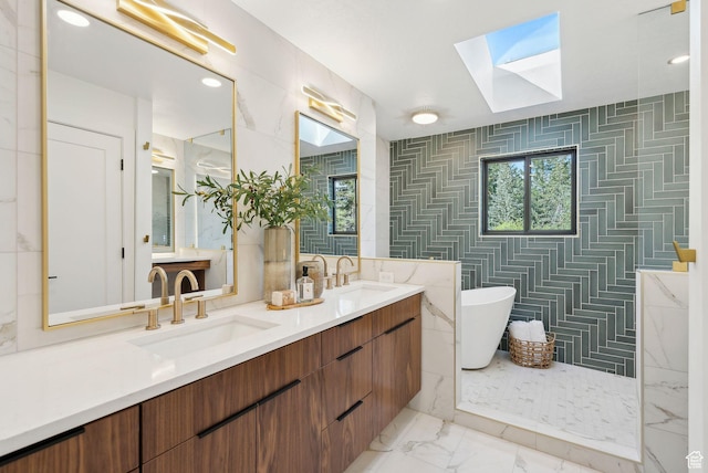 full bathroom featuring a skylight, a freestanding tub, marble finish floor, and a sink