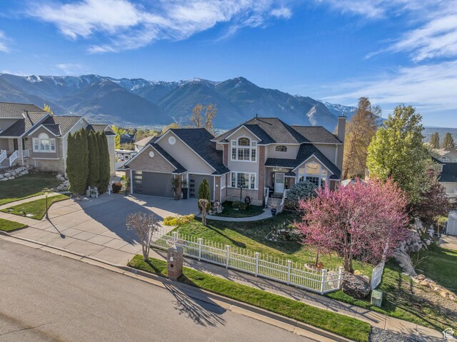305 E 3700 N, North Ogden, UT 84414 - traditional-style house featuring a fenced front yard, a mountain view, a chimney, concrete driveway, and an attached garage