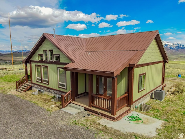 rear view of property featuring a porch, central AC, a mountain view, and metal roof