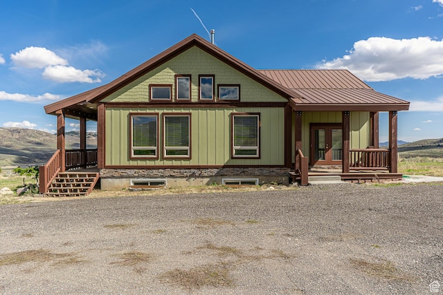 exterior space featuring board and batten siding, a porch, french doors, and a mountain view