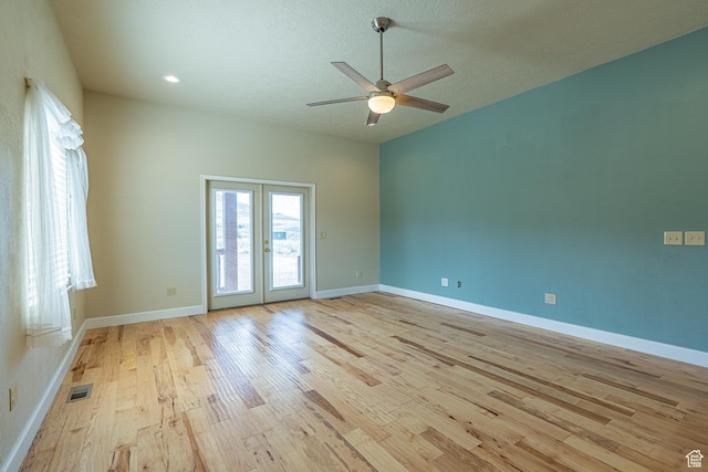 spare room featuring french doors, light wood-style flooring, baseboards, visible vents, and ceiling fan