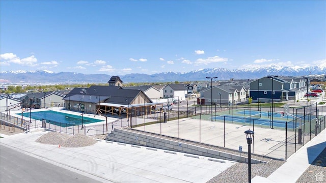 pool with fence, a residential view, and a tennis court