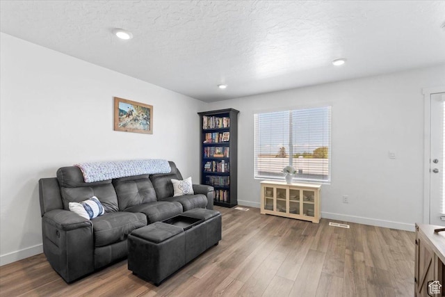living area with wood finished floors, a textured ceiling, and baseboards