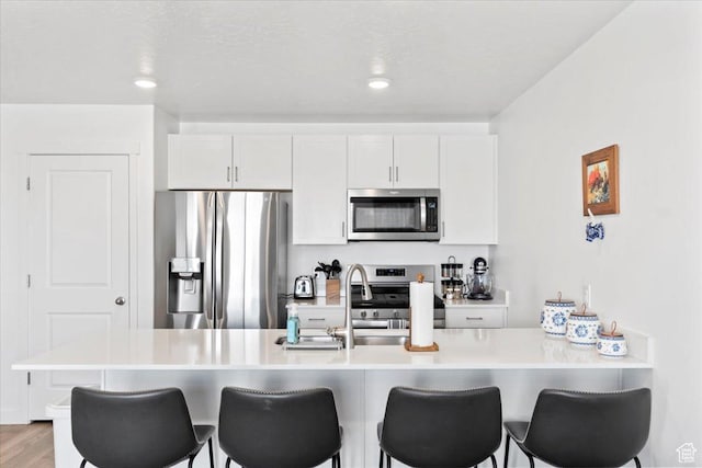 kitchen with light countertops, stainless steel appliances, a breakfast bar, and a sink
