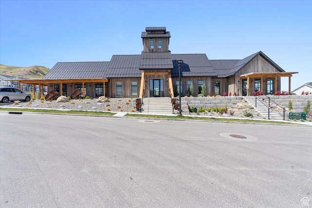 view of front facade with metal roof, a standing seam roof, stairs, and board and batten siding