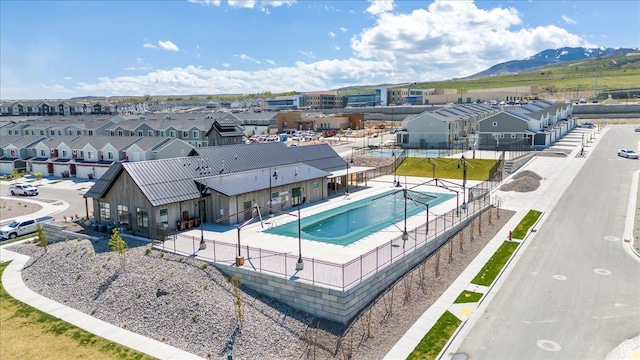 community pool with a residential view, a patio, fence, and a mountain view