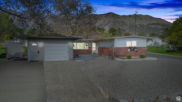 ranch-style house featuring brick siding, an attached garage, concrete driveway, and a mountain view