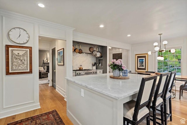 1904 E Yalecrest Ave S, Salt Lake City, UT 84108 - kitchen with stainless steel gas stove, ornamental molding, a kitchen island, light stone countertops, and light wood-style flooring
