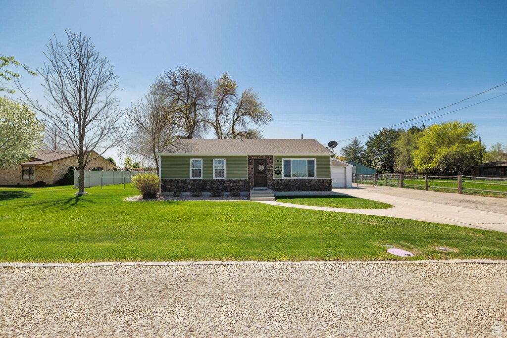 4075 W 2600 N, Plain City, UT 84404 - bungalow-style home featuring fence, a front lawn, concrete driveway, stone siding, and a garage