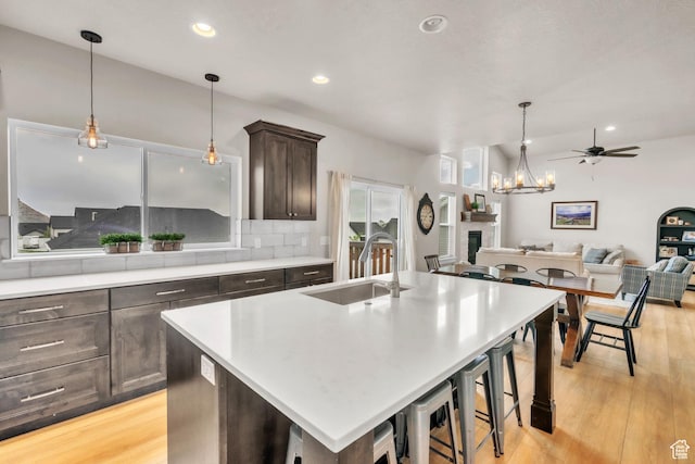 1153 E 2850 N, North Ogden, UT 84414 - kitchen featuring light wood finished floors, a sink, tasteful backsplash, dark brown cabinets, and light countertops