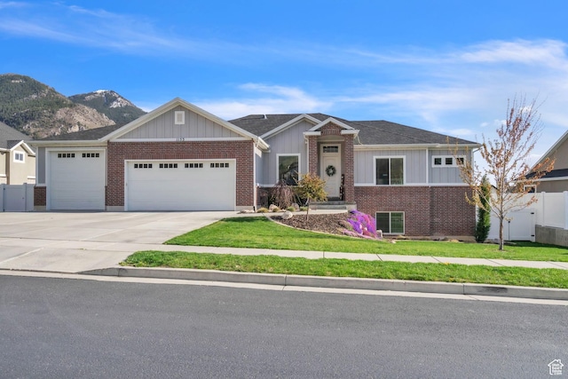 1153 E 2850 N, North Ogden, UT 84414 - view of front of house featuring a front lawn, driveway, board and batten siding, an attached garage, and brick siding