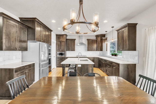 1153 E 2850 N, North Ogden, UT 84414 - kitchen with an island with sink, dark brown cabinets, wall chimney range hood, a chandelier, and appliances with stainless steel finishes
