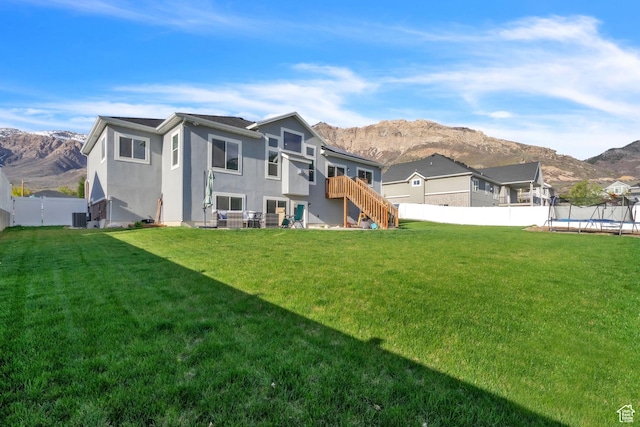 1153 E 2850 N, North Ogden, UT 84414 - rear view of house with a fenced backyard, a mountain view, a trampoline, and stucco siding
