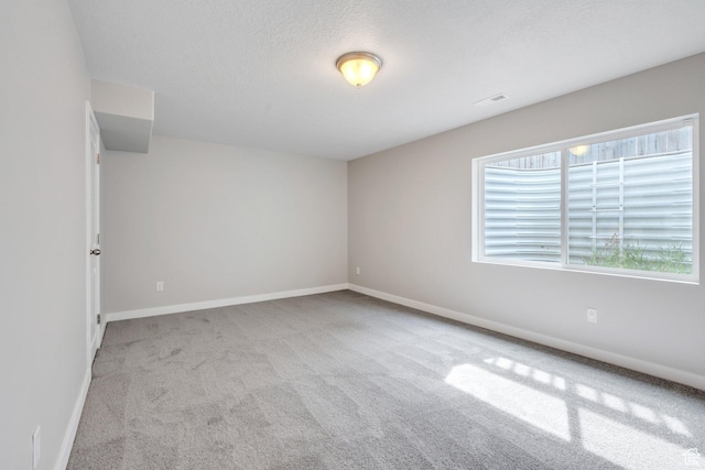 carpeted empty room featuring visible vents, baseboards, and a textured ceiling