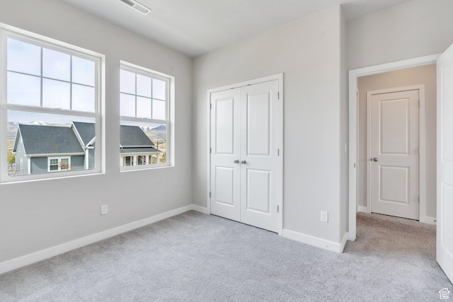 unfurnished bedroom featuring baseboards, visible vents, carpet floors, and a closet