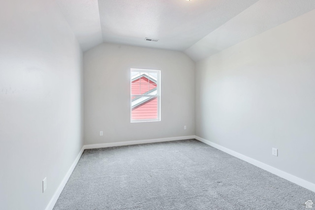 unfurnished room featuring baseboards, lofted ceiling, visible vents, and carpet