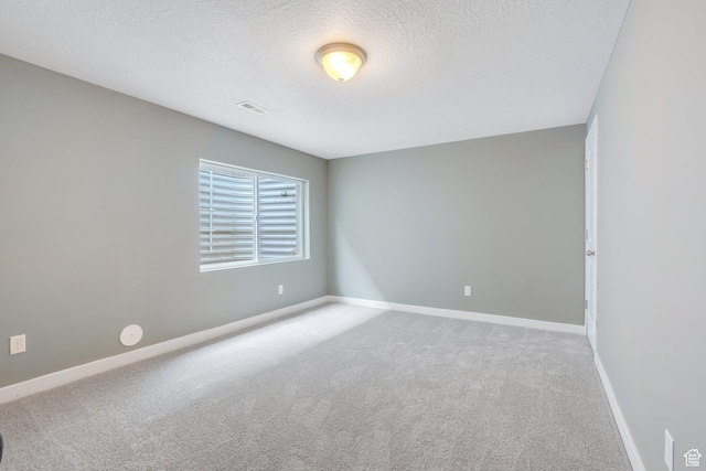 spare room featuring a textured ceiling, carpet floors, visible vents, and baseboards
