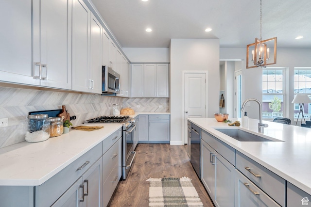 kitchen featuring tasteful backsplash, gray cabinetry, stainless steel appliances, and a sink