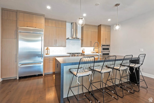 801 E Klaim Dr N, Hideout, UT 84036 - kitchen with stainless steel appliances, wall chimney exhaust hood, light brown cabinetry, a breakfast bar, and a center island with sink