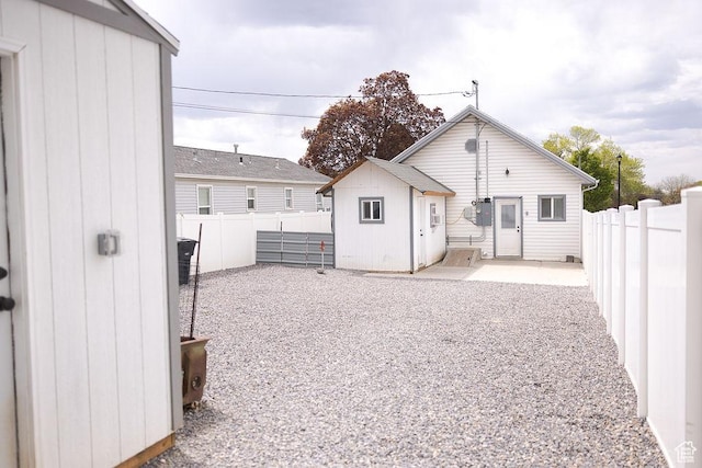 rear view of property with a fenced backyard, an outbuilding, a patio area, and a storage unit