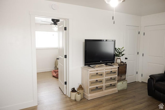 living area with ceiling fan, baseboards, and wood finished floors