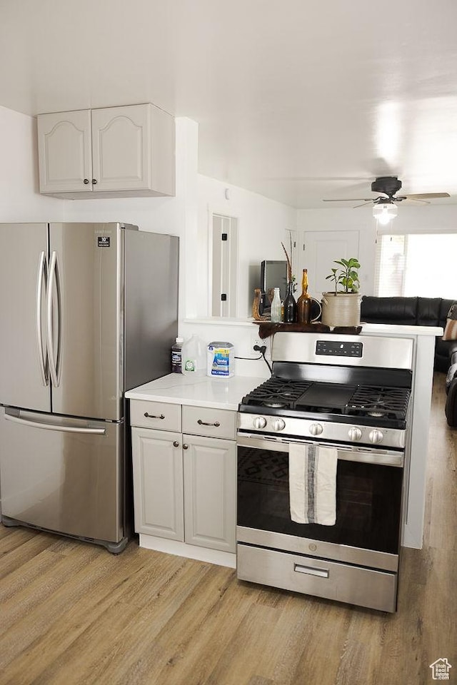 kitchen featuring white cabinets, stainless steel appliances, a ceiling fan, and light wood-style floors