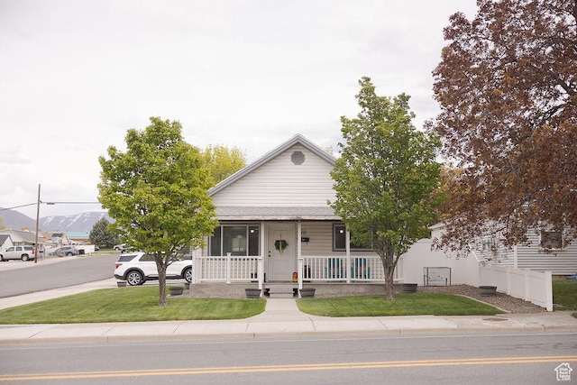 view of front facade with a porch, a front lawn, and fence