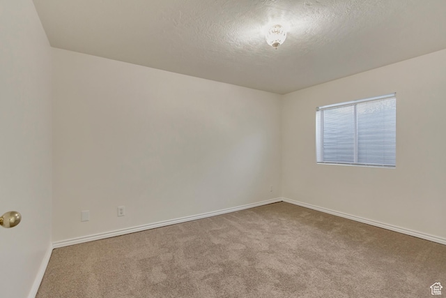 carpeted empty room with baseboards and a textured ceiling