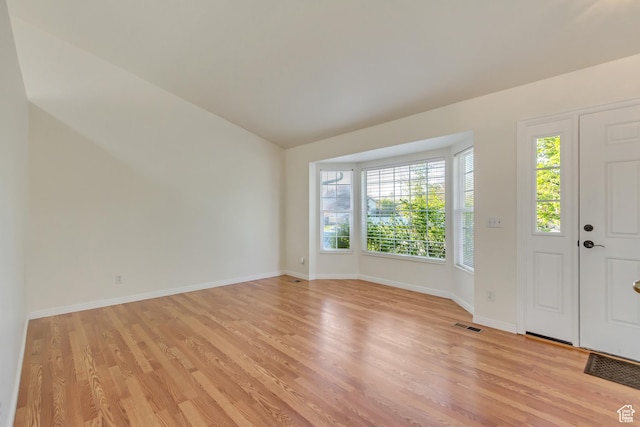 foyer featuring lofted ceiling, visible vents, light wood finished floors, and baseboards