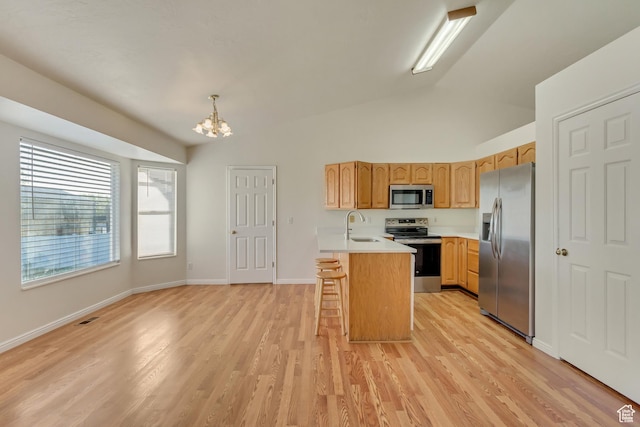 kitchen with a peninsula, a sink, an inviting chandelier, light countertops, and appliances with stainless steel finishes