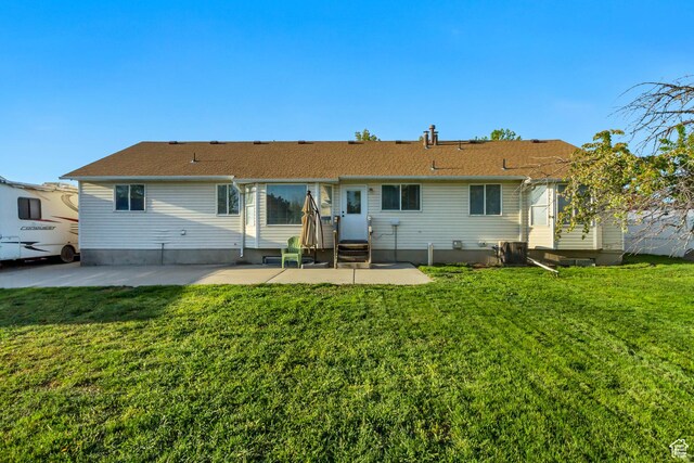 back of house featuring entry steps, a lawn, and a patio