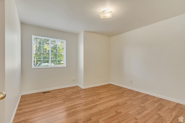 empty room featuring visible vents, light wood finished floors, and baseboards