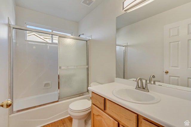 bathroom with toilet, visible vents, wood finished floors, vanity, and enclosed tub / shower combo