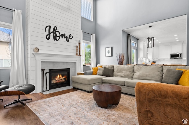 322 Flour Mill Dr, Kaysville, UT 84037 - living area featuring a tile fireplace, wood finished floors, a wealth of natural light, and a high ceiling