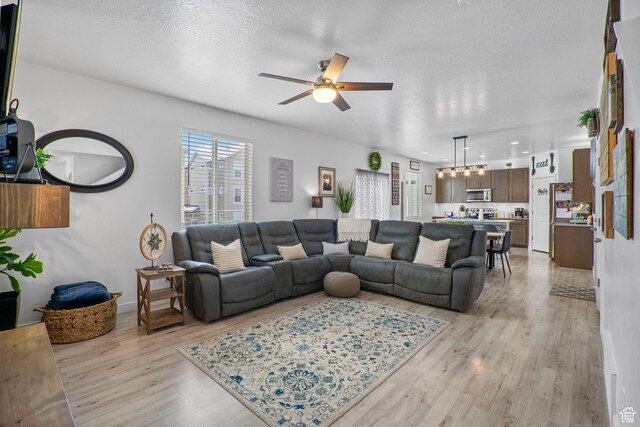 13137 S Acklins Dr, Herriman, UT 84096 - living area with light wood-type flooring, a textured ceiling, baseboards, and ceiling fan with notable chandelier