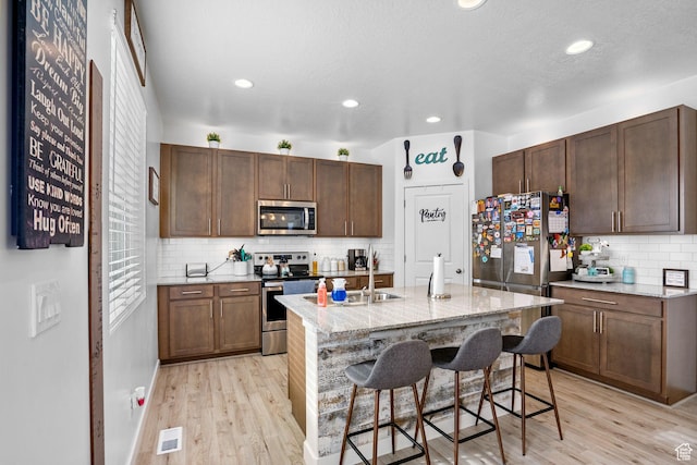 13137 S Acklins Dr, Herriman, UT 84096 - kitchen with a kitchen breakfast bar, light wood-style flooring, backsplash, appliances with stainless steel finishes, and visible vents