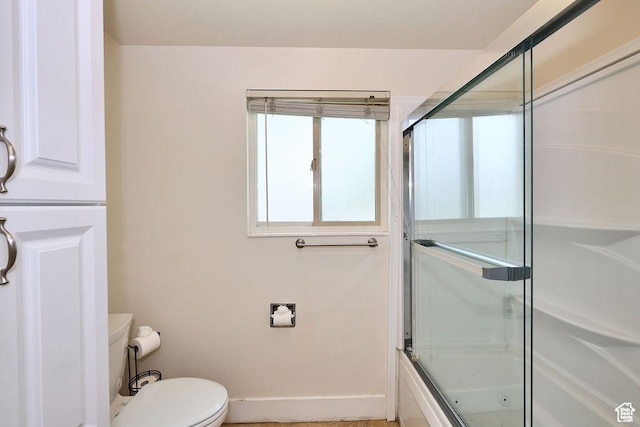 full bathroom featuring combined bath / shower with glass door, toilet, and baseboards