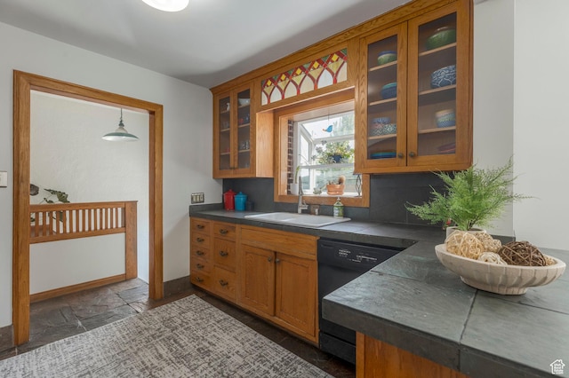 kitchen with a sink, brown cabinetry, glass insert cabinets, dishwasher, and stone tile flooring