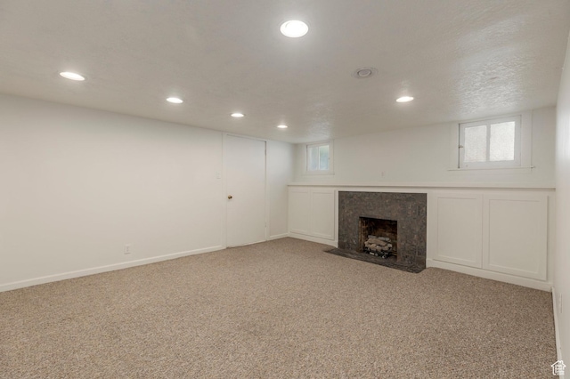 below grade area featuring carpet, a high end fireplace, and recessed lighting