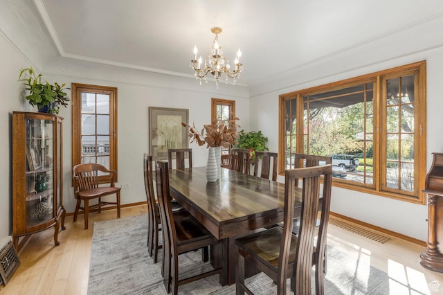 dining area with visible vents, light wood finished floors, baseboards, and a notable chandelier